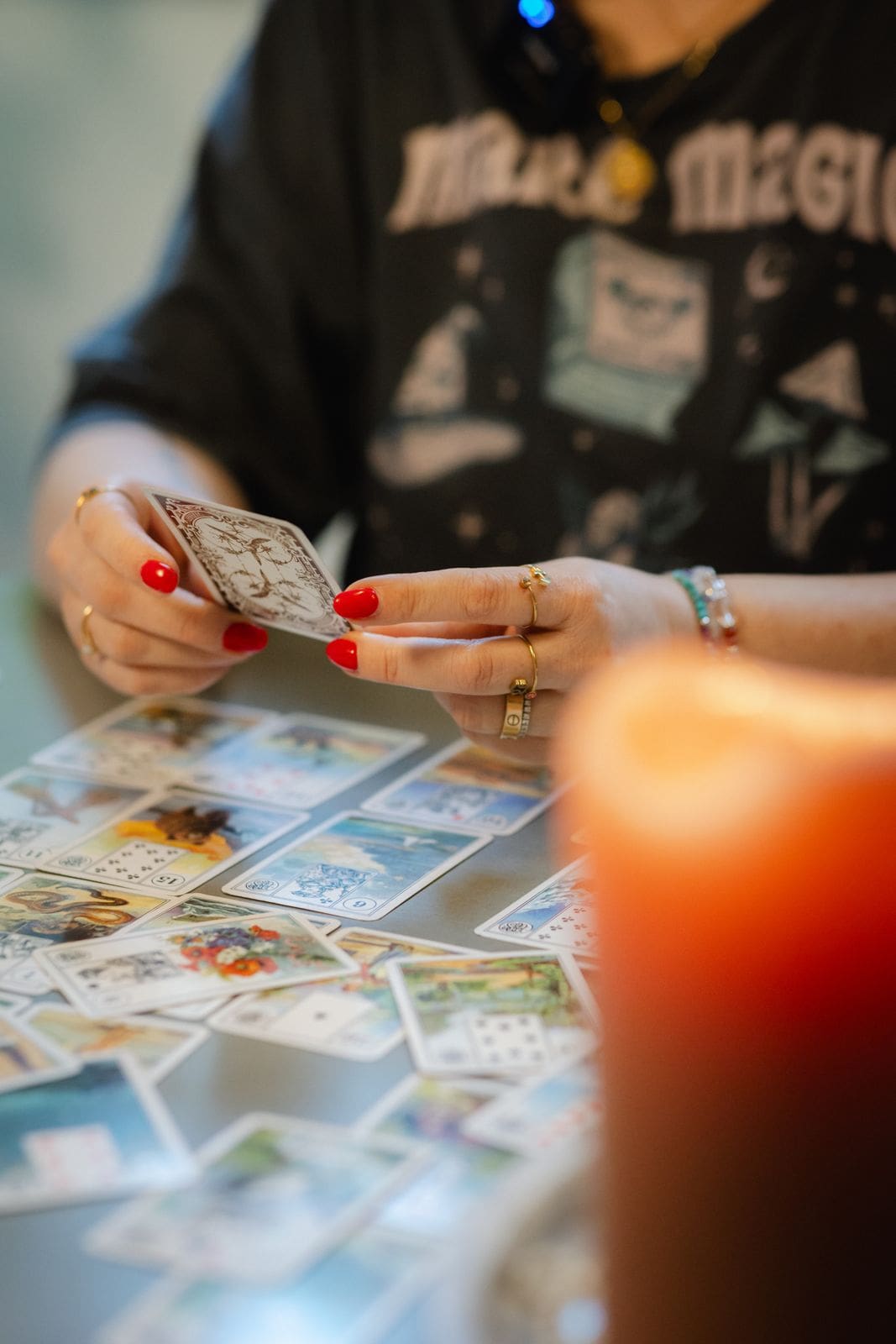 Lenormand-Karten in der Hand, daneben eine brennende Kerze